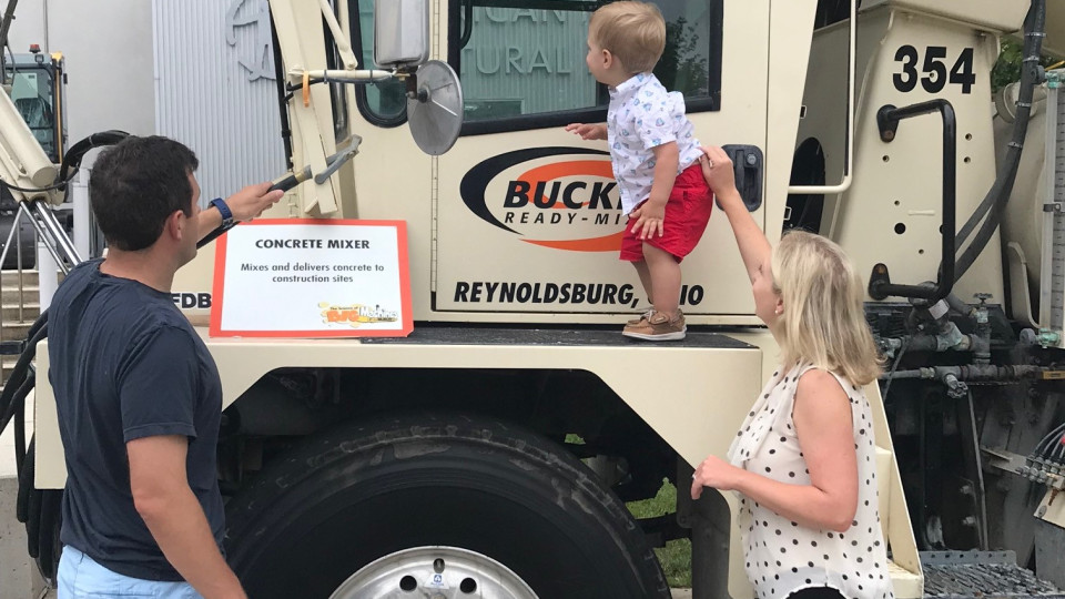 Small child on concrete truck with parents